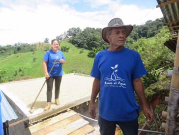 Man and woman working on structure while wearing 'Manos al Agua' t-shirts