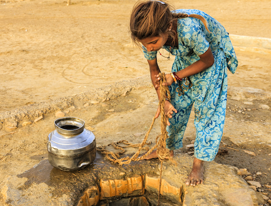 Indian young girl drawing water from a well, Rajasthan