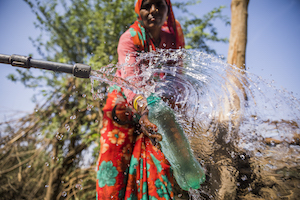 woman collecting water into bottle from faucet