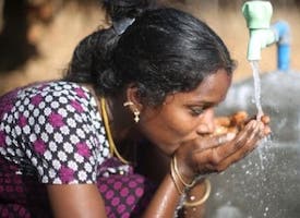 woman drinking water from faucet